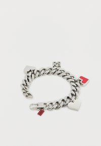 Ασημένιο βραχιόλι αλυσίδας με τρία γούρια: μια κόκκινη καρδιά, μια γεωμετρική καρδιά και μια μικρή κόκκινη ετικέτα με το κείμενο "NICO".