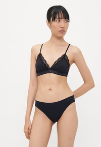 Zwart lingerieset met een bralette met kantafwerking en dunne bandjes, gecombineerd met een bijpassende bikini onderkant. Gladde stoftextuur.