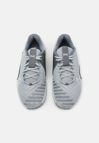 Szare buty sportowe z siateczkową cholewką, teksturowanymi detalami i płaskimi sznurówkami. Posiadają wzmocniony nosek oraz wyraźne logo marki po boku.