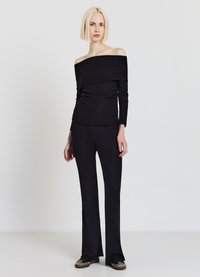 Schwarzes, geripptes Off-Shoulder-Top kombiniert mit passenden ausgestellten Hosen. Das Ensemble zeichnet sich durch einen strukturierten Stoff, eine schlanke Passform und ein nahtloses Design aus.