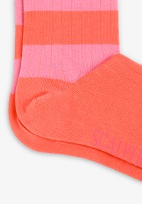 Calcetines a rayas en rosa y coral, con una textura acanalada, tejido suave y detalle del logo en coral. Diseñados para un ajuste ceñido.