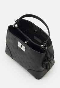 Sort struktureret håndtaske i tekstureret materiale med sølvhardware, der har en trykknaplukning og sidepuster detaljer. Indvendigt har den rum.