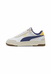 Puma CA Match sneakers feature a white leather upper with blue and yellow accents, a textured beige sole, and punctured detailing on the sides.