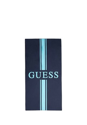 Asciugamano rettangolare blu navy con due strisce verticali azzurro chiaro e la parola "GUESS" in azzurro chiaro centrata tra le strisce.