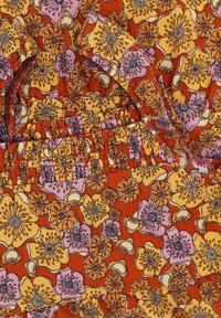 Bloemrijke textiel met oranje, gele en paarse tinten. Bevat ingewikkelde bloemenpatronen met gedetailleerde omtrekken en textuurstof.