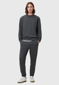 Sudadera gris oscuro y joggers a juego hechos de una tela suave. Presenta puños y cintura acanalados, con un discreto detalle del logotipo en el pecho.