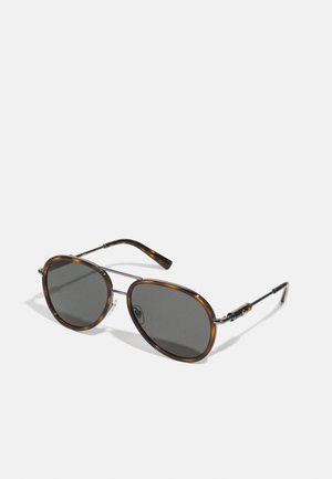 Óculos de sol de tartaruga com lentes cinzas, forma oval, detalhes em metal e hastes finas, apresentando um design de armação em duas tonalidades e almofadas deslizantes para o nariz.