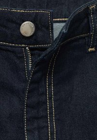 Dunkelblaue Jeanshose mit Reißverschluss, Messingknopfverschluss und kontrastierenden gelben Nähten entlang der Nähte und Taschen.