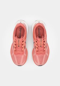 "Nike" bėgimo bateliai koralų rožinės spalvos, su tinklelio viršutine dalimi, paminkštintu apvadu ir baltu padu. Su logotipu ir pagalvėlės detalėmis.