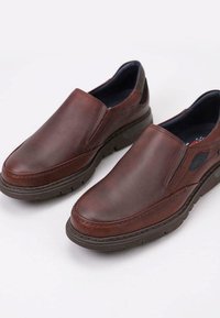 Chaussures en cuir brun à enfiler avec une surface lisse, semelle intérieure rembourrée et semelle en caoutchouc texturée. Comprend des panneaux latéraux élastiques pour un enfilage facile.