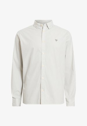 Pasiasta koszula z guzikami w jasnym beżu i bieli. Posiada klasyczny kołnierzyk, długie rękawy oraz małą haftowaną emblemat na piersi.