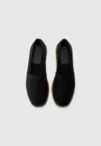 Crne platnene espadrile s utisnutim Calvin Klein logom, okrugli vrh, elastične strane i đon od prirodnih vlakana s vidljivim šavovima.