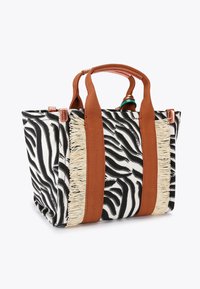 Torba typu tote w wzór zebry z brązowymi szerokimi uchwytami z tkaniny oraz kremowym frędzlami po bokach na białym tle.