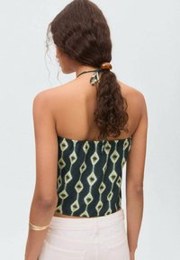 Top cropped senza spalline con uno sfondo scuro e un motivo a diamante in giallo e crema. Presenta un retro elasticizzato e un dettaglio con fiocco.
