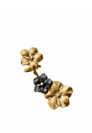 Tres anillos conectados con forma de flor, dos dorados y uno negro, cada uno con una pequeña piedra preciosa central transparente.