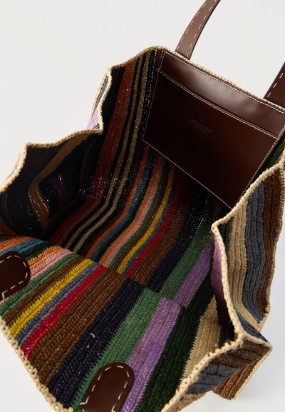 Sac fourre-tout tissé multicolore rayé avec des poignées en cuir et une poche intérieure en cuir brun.