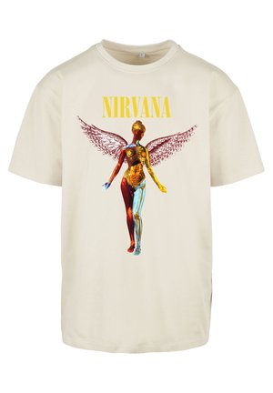 Cream-colored cotton t-shirt featuring a large graphic of a figure with anatomical details and wings, emblazoned with "NIRVANA" in bold yellow.