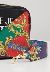 Versace Jeans Couture pung med sort læder, farverigt mønstret stof, gylden lynlås og aftagelig rem med intrikate design.