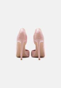 Ροζ παπούτσια με ψηλό τακούνι από δέρμα λάκας, με μυτερή μύτη και λεπτό τακούνι στιλέτο, που παρουσιάζουν μια ομαλή, γυαλιστερή επιφάνεια.