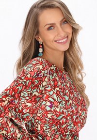 Bluză cu model floral roșu, cu mâneci lungi, având accente turcoaz și corai. Material ușor, design fluid și decolteu rotund.