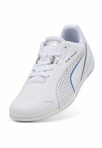 Sneaker bianco con design perforato, linguetta in mesh, dettagli blu e rossi, e suola in gomma. Loghi del marchio presenti sul lato e sulla linguetta.