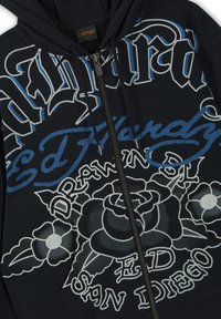 Schwarzer Kapuzenpullover mit Reißverschluss, versehen mit gotischem und kursivem Text, der "Ed Hardy", "Drawn" und florale Tattoo-Designs in Weiß und Blau zeigt.