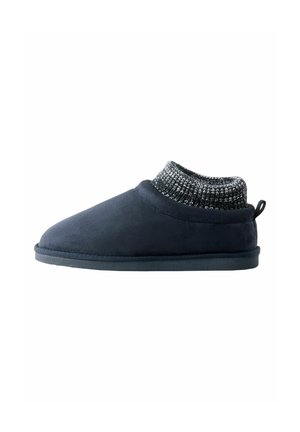 Papuci de culoare albastru închis cu un exterior moale din suede și un guler tricotat, texturat. Au o talpă plată și o etichetă la spate pentru a fi ușor de purtat.