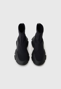 Bottines noires avec un design épuré, fabriquées dans un matériau lisse, dotées d'une tige haute, d'un bout rond et d'une semelle texturée pour une meilleure adhérence.