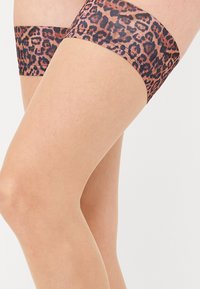 Calze alti fino alla coscia con stampa leopardata e base trasparente, caratterizzate da un design audace lungo la fascia superiore e una superficie liscia.