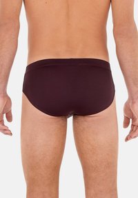 Bordeauxrote Schwimmbrieftasche mit glatter Textur, elastischem Bund und minimalistischem Design, das eine enganliegende Passform bietet und keine sichtbaren Muster oder Akzente aufweist.