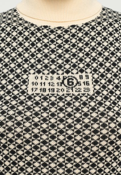 Stickad tröja i svart och off-white med ett geometriskt mönster. Har en ribbad rund halsringning och en logotyp som är placerad centralt.