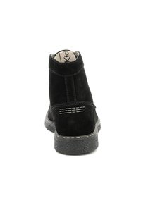 Botas de tobillo de ante negro con una superficie texturizada, costuras visibles y suela de goma. El diseño presenta un talón alto y un detalle mínimo.