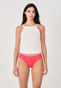 Weißes, geripptes Tanktop mit dünnen Trägern, kombiniert mit glänzenden roten Bikinihöschen. Eng anliegend, mit glatter Textur und schlichtem Design.