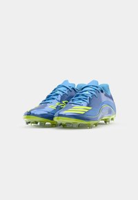 Blue soccer cleats with yellow accents, featuring a smooth synthetic upper, lace closure, and traction studs on the green sole.