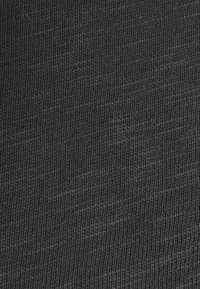 Ciemnoszara dziana tkanina o gładkiej fakturze, z jednolitym wzorem i subtelnymi różnicami w odcieniach.