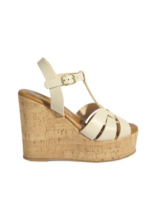 Beige leather wedge sandal with cork platform sole, T-strap design, and gold buckle closure.