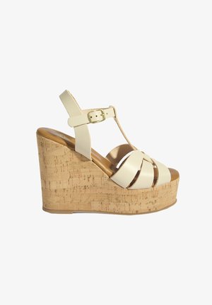 Sandale compensée en cuir beige avec semelle plateforme en liège, design à bride en T et fermeture à boucle dorée.