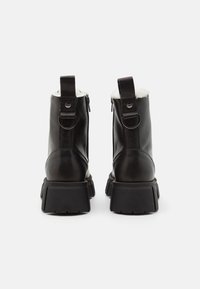 Schwarze Leder-Stiefeletten mit einer robusten Gummisohle, mit einem Reißverschluss, Schlaufen-Detail und einem weichen weißen Futter für zusätzlichen Komfort.