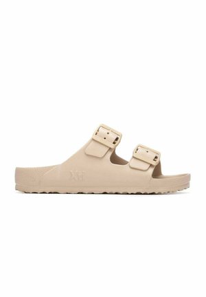 Sandalia beige sin cierre con dos tiras ajustables con hebillas y suela texturizada, diseñada para uso casual.