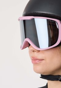 Vaaleanpunaiset laskettelulasit leveällä, kaarevalla linssillä ja mustalla kehyksellä. Säädettävä hihna varmistaa hyvän istuvuuden. Heijastava tummalasi ja tyylikäs muotoilu.