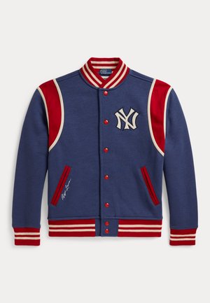 Blå varsityjakke med røde og hvide stribede krave, manchetter og kant, røde skulderpaneler, røde knapper og et hvidt New York Yankees-logo.