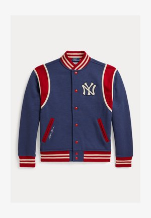 Modra športna jakna z rdeče-belimi črtastimi ovratnikom, manšetami in robom, rdečimi ramenskimi paneli, rdečimi gumbi in belim logotipom New York Yankees.