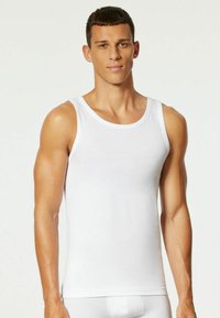 White tank top made of soft cotton, featuring a crew neck design and wide shoulder straps. Smooth texture with no patterns or embellishments.