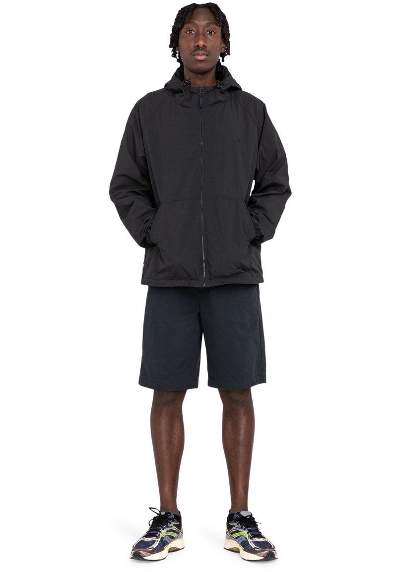 Sort hættetrøje med lynlås, to frontlommer, parret med mørke shorts og multicolore sneakers. Letvægtsmateriale, afslappet pasform.