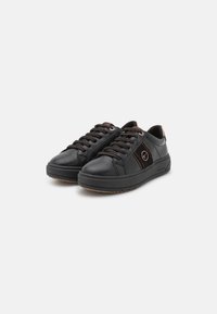Zapatillas de cuero negro con cordones marrones y acentos, punta redondeada, suela plana y detalle de logo en el lateral. Textura suave y diseño minimalista.