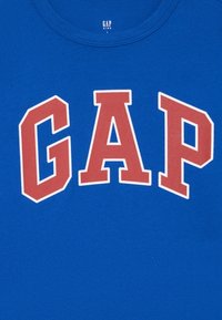 Kék pamut póló, kerek nyakkivágással, élénk piros "GAP" felirattal, fehér keretben. Címke szerint "GAP KIDS", nagy méret.