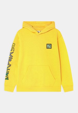 Yellow hoodie with a front pocket, drawstring hood, and a logo patch on the chest. Features colorful text along the left sleeve. Cotton material.
