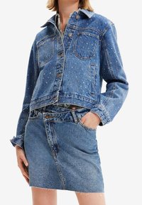 Jeansjacka med färgglada pärldekorationer, med klassisk krage, knappstängning och två framfickor. I kombination med en jeansminikjol.