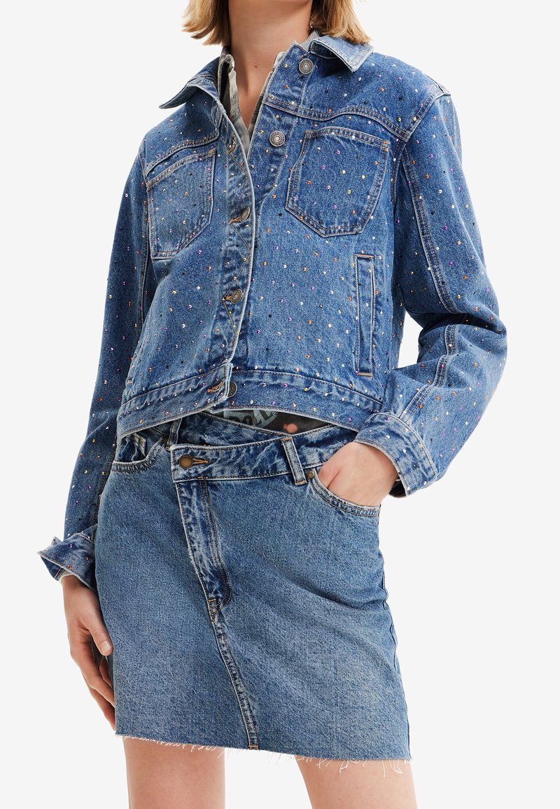 Jeansjacka med färgglada pärldekorationer, med klassisk krage, knappstängning och två framfickor. I kombination med en jeansminikjol.