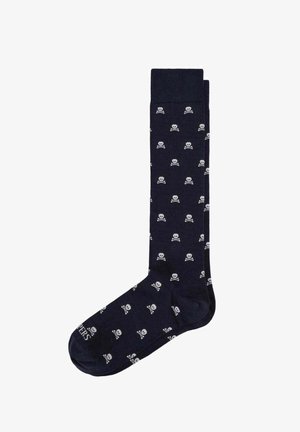 Calcetín azul marino hasta la rodilla con un patrón repetido de pequeñas calaveras y huesos cruzados blancos.